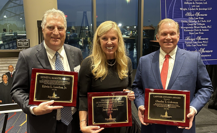 Three lawyers holding award plaques at an event.