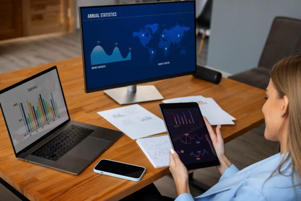 Woman analyzing business statistics on tablet and laptop.