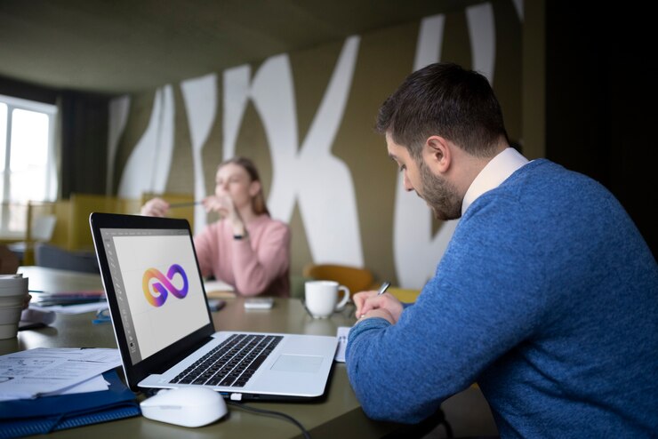 Man working on laptop, creative office setting.